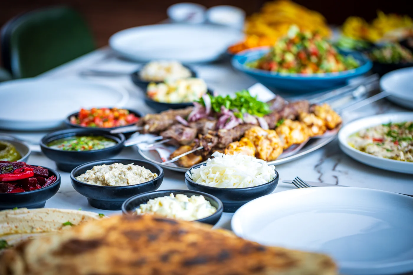 שולחן אירוח ארוך עם מגוון סלטים, ממרחים ולאפה טרייה
