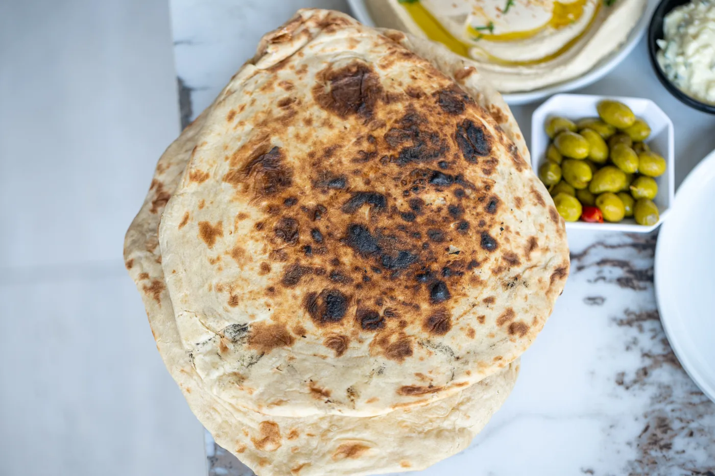 לאפה טרייה אפויה בטאבון לצד זיתים וחומוס